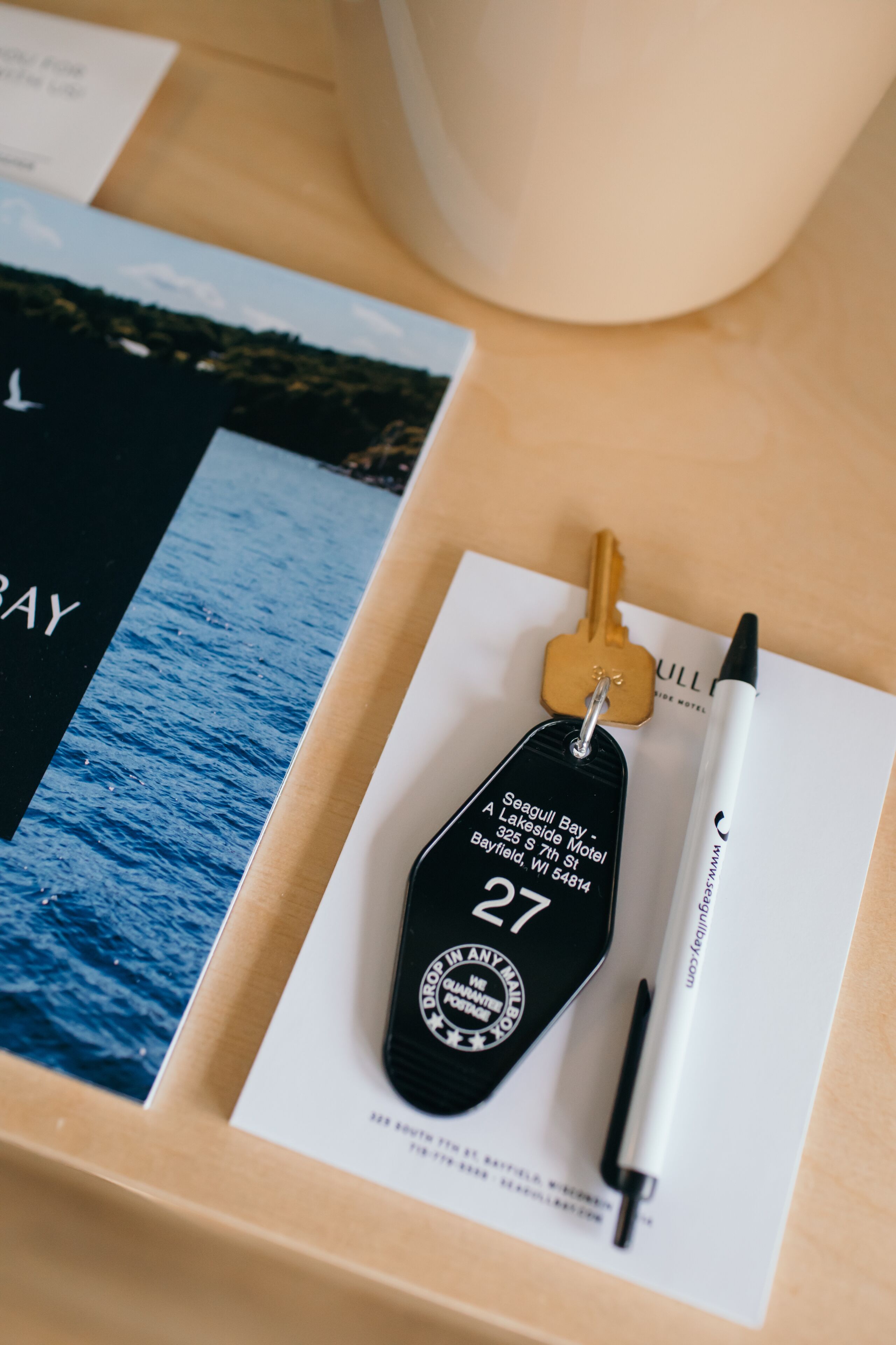 A key, a pen, and a printed card on a wooden surface.