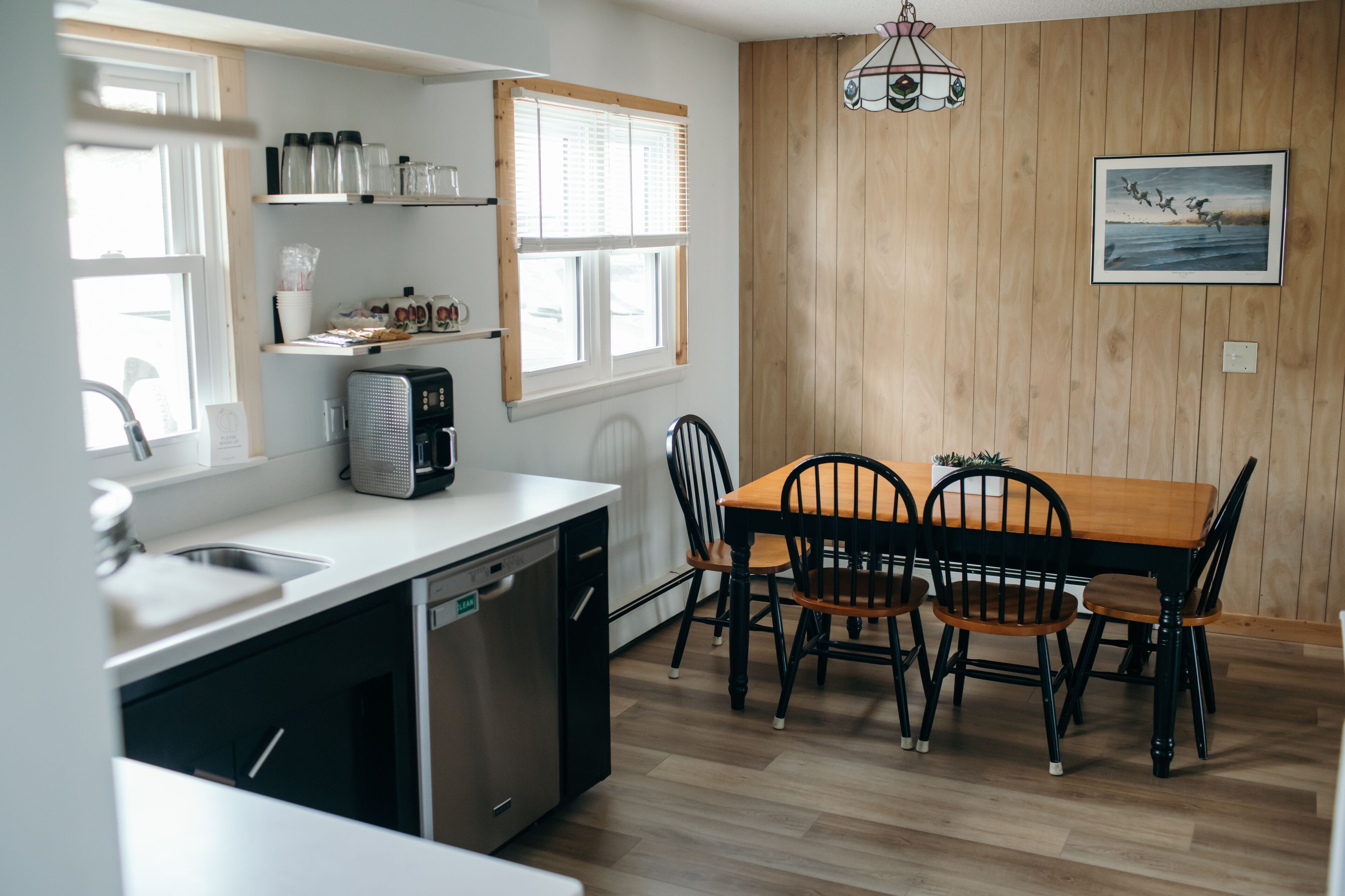 A kitchen with a dishwasher, a stove, and a dining table with chairs.