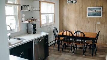 A kitchen with a dishwasher, a stove, and a dining table with chairs.