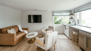 A modern living room with a sofa, armchairs, a coffee table, and a TV mounted on the wall. - Seagull Bay Motel (Bayfield)