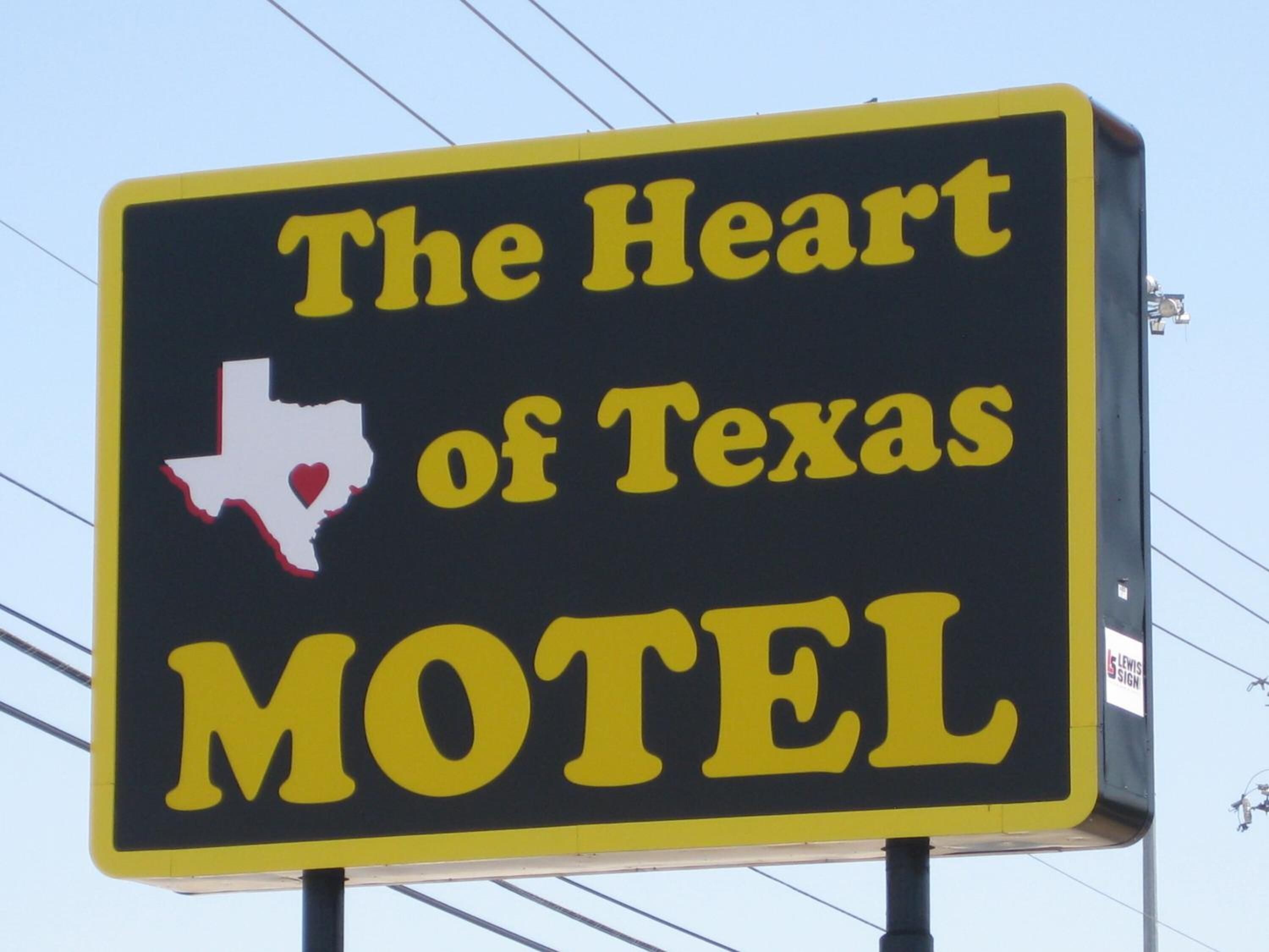 A sign for 'The Heart of Texas Motel' with a Texas outline and heart symbol.