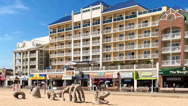 Een hotel met meerdere verdiepingen, balkons, een ligging aan het strand en diverse winkels en restaurants.