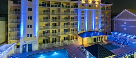 A multi-story hotel with a pool area, including sun loungers and a smaller pool.