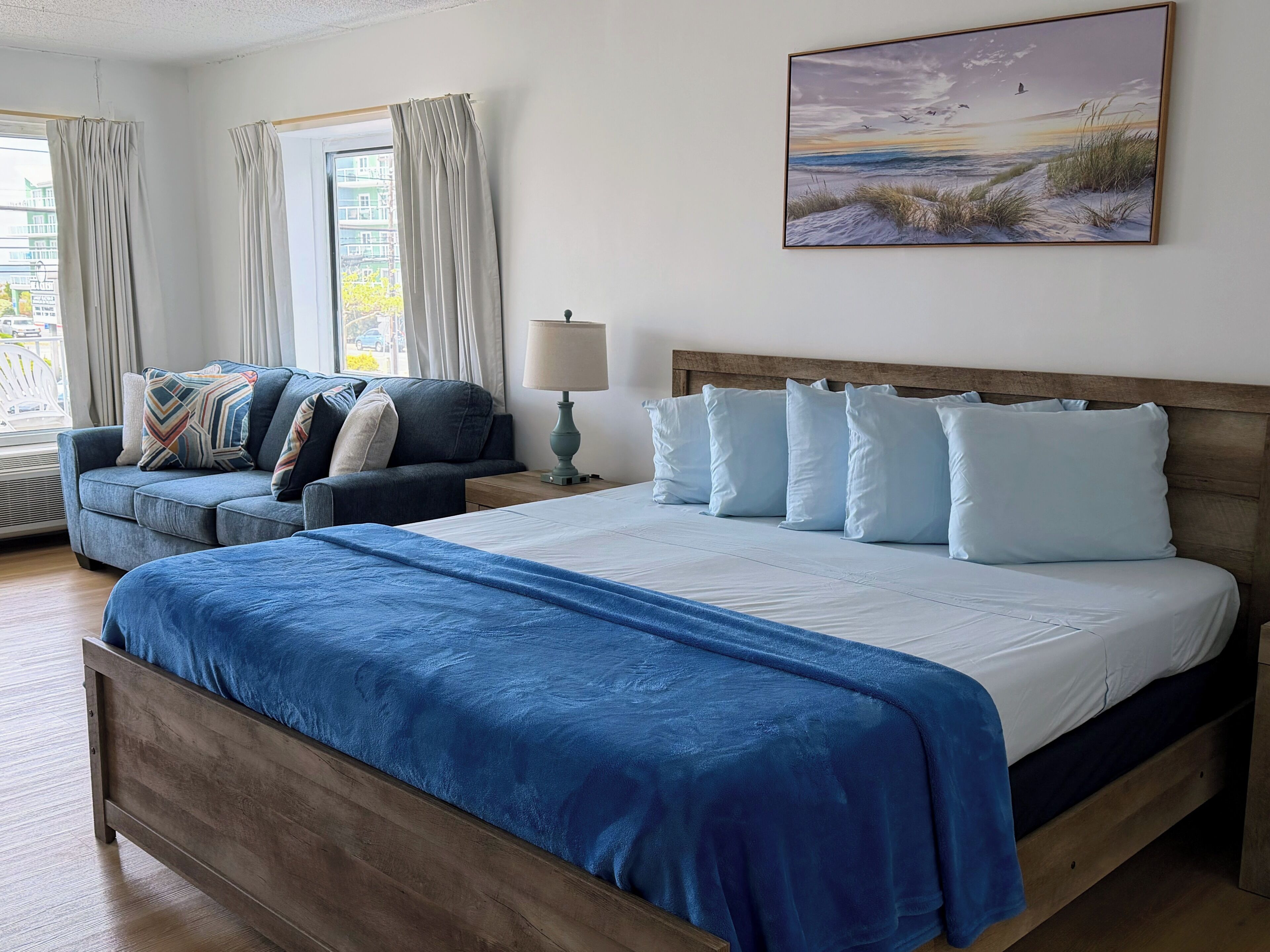 Un dormitorio con una cama grande, un sofá, una lámpara y un cuadro en la pared.