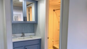 A bathroom with a sink, mirror, cabinet, and toilet.