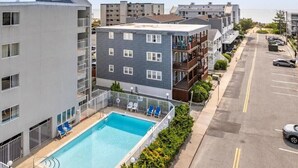 A multi-story building with a rooftop pool, balconies, and a parking area.
