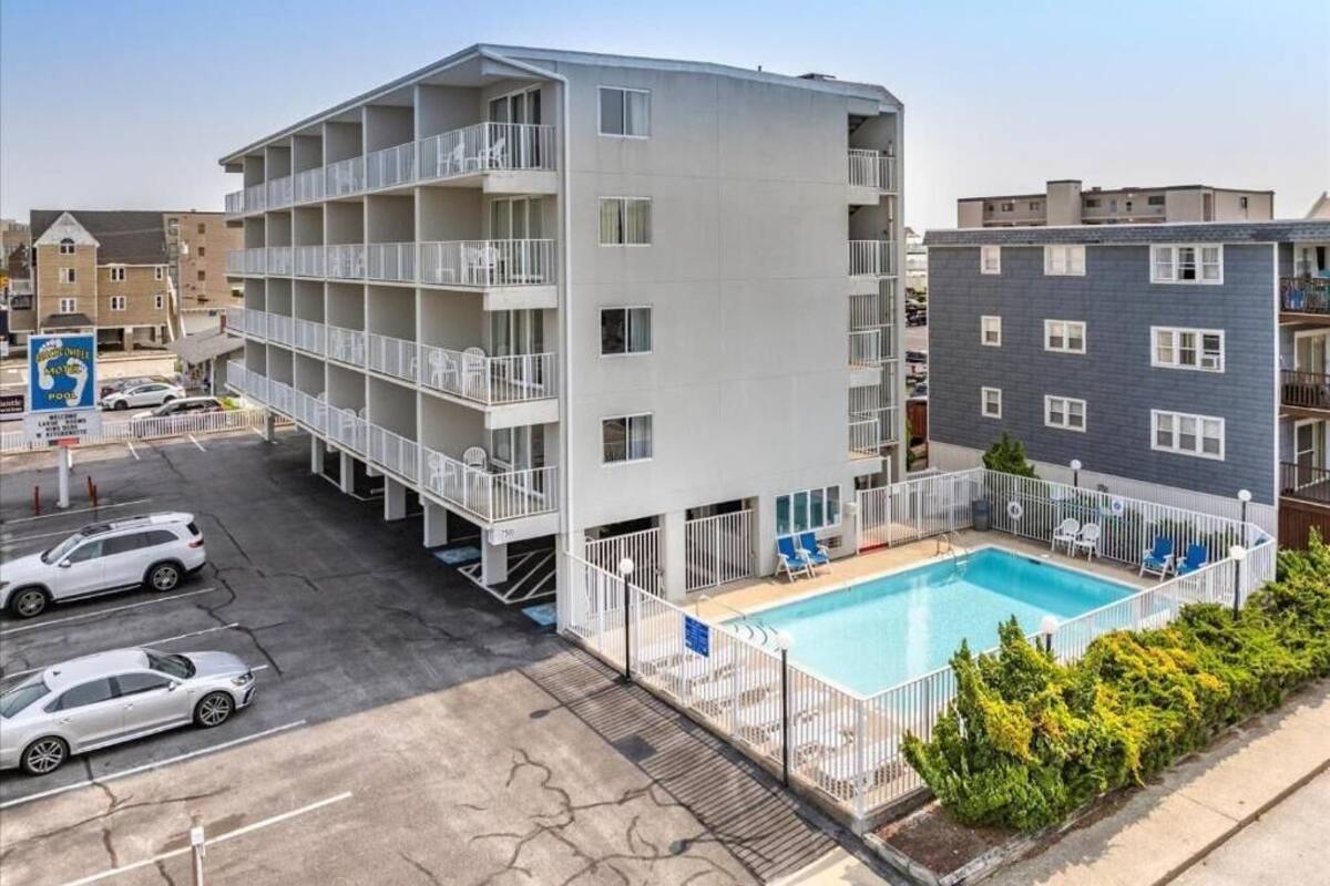 Ein mehrstöckiges Hotel mit Balkonen, einem Swimmingpool und einem Parkplatz.