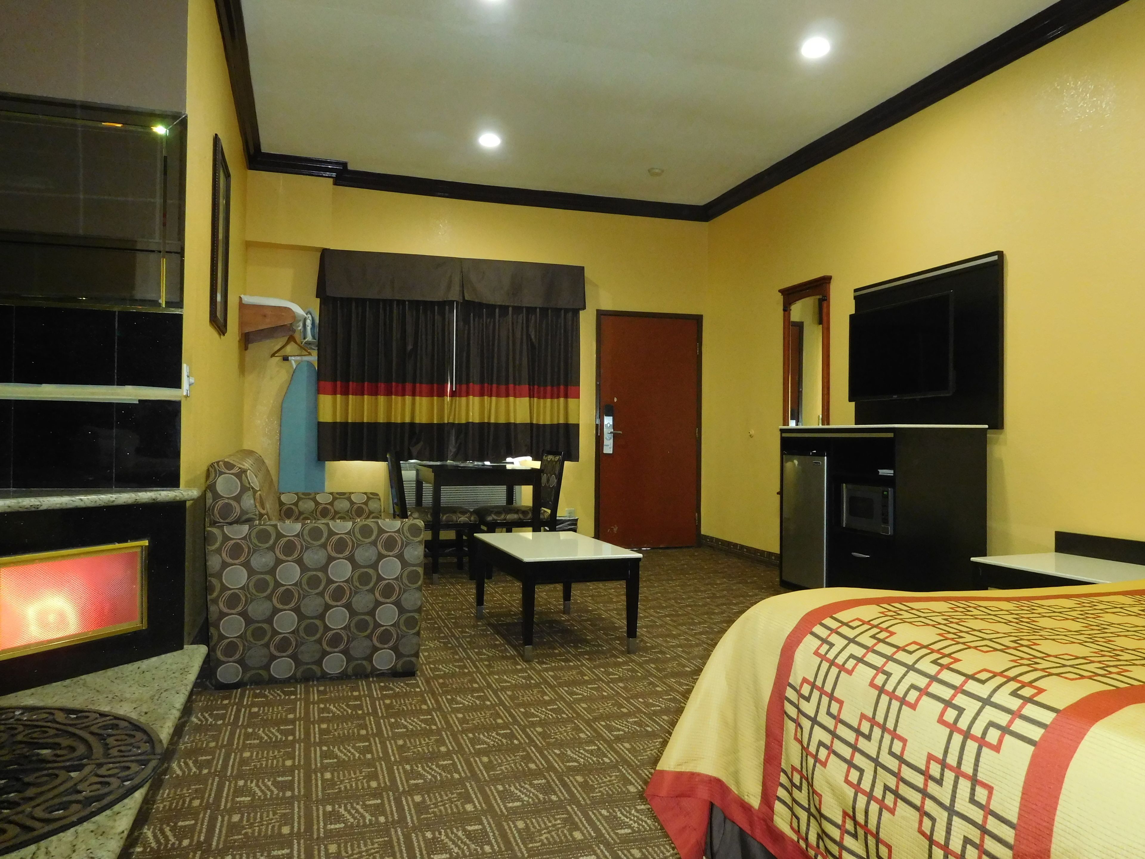 Quarto de hotel com cama, televisão, escrivaninha e cadeira.
