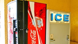 A vending machine with a Coca-Cola logo and a self-serve ice machine next to it.
