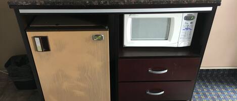 A compact kitchenette with a microwave, a small refrigerator, and a drawer unit.