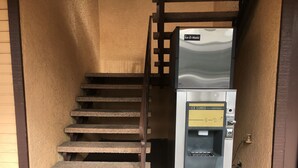 A staircase leading to a room with a vending machine labeled "Ice-O-Matic" and "Ice Cubes" for dispensing ice. - Del Amo Inn (Torrance)