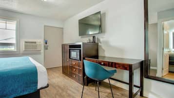 A hotel room with a bed, a desk, a chair, a TV, and a wardrobe.