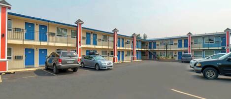 A motel with multiple rooms, a parking lot, and several parked cars.