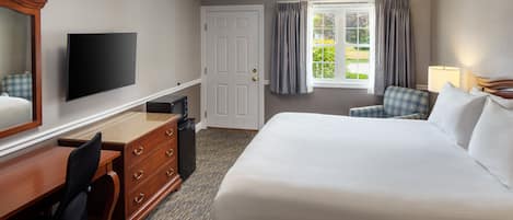 Une chambre d’hôtel avec un grand lit, un bureau avec une chaise, une télévision et une fenêtre avec des rideaux.