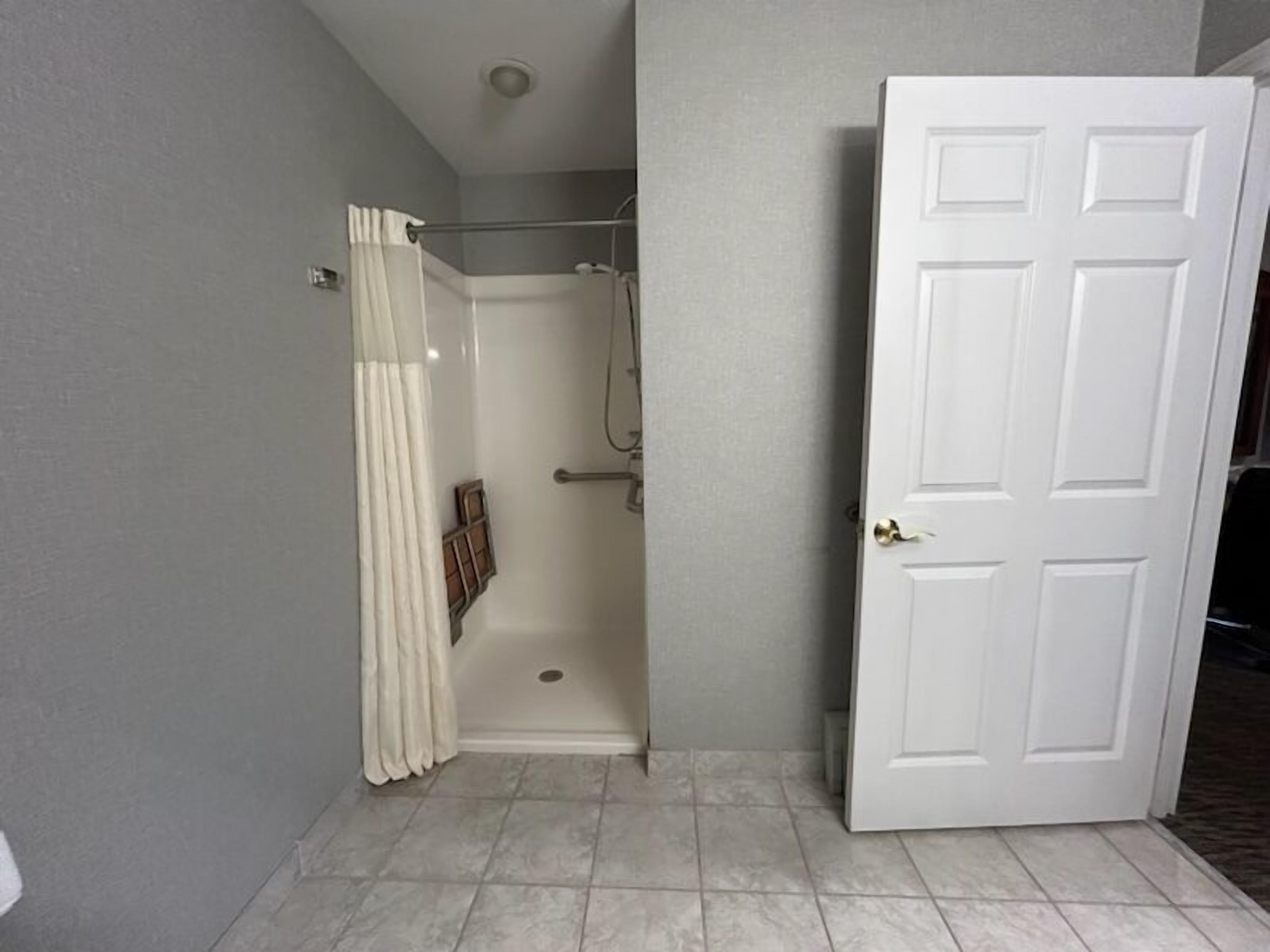 A bathroom with a shower, a door, and tiled flooring.