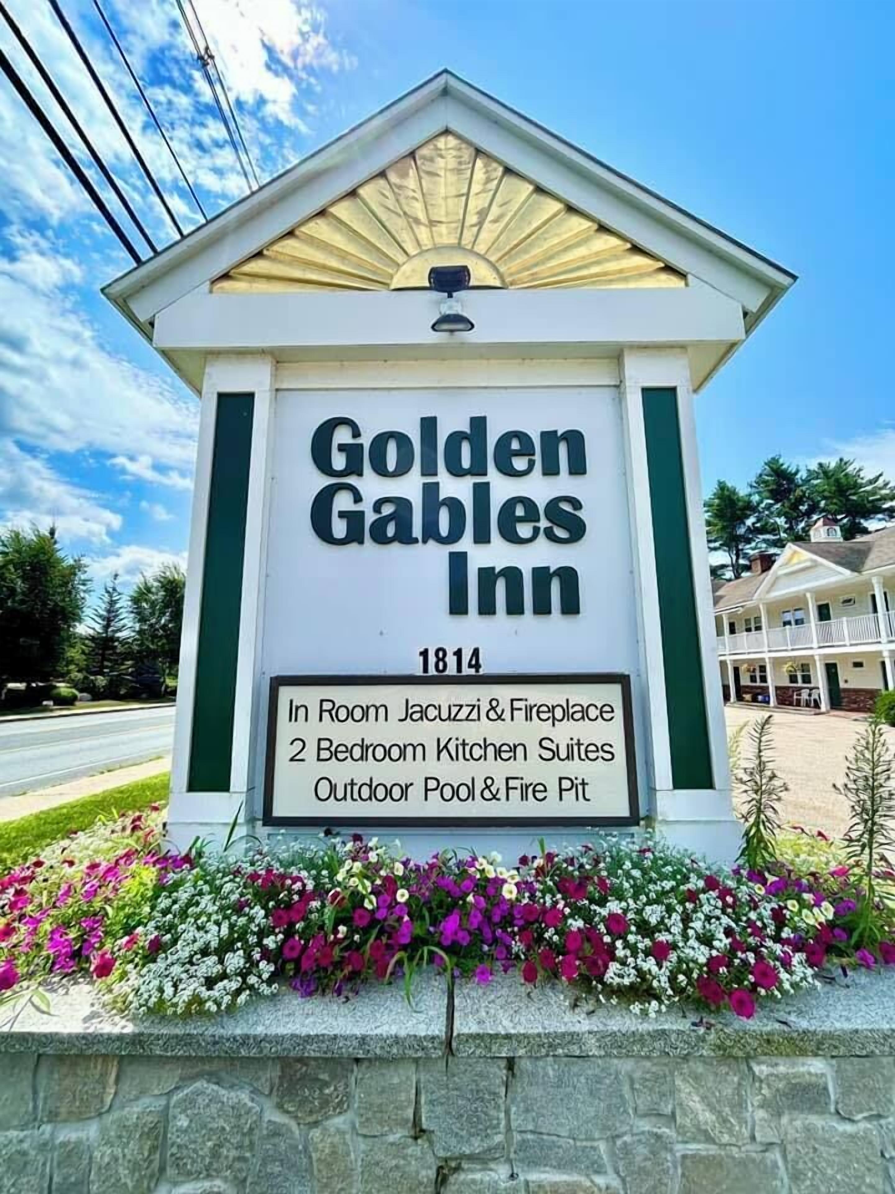 A sign for the Golden Gables Inn, listing amenities like in-room jacuzzi and fireplace, 2 bedroom kitchen suites, outdoor pool, and fire pit.