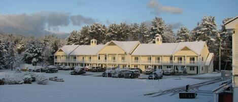 A motel with multiple rooms, a parking lot, and snow-covered trees.