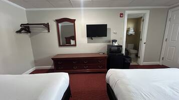 A hotel room with two beds, a dresser, a television, and a microwave.