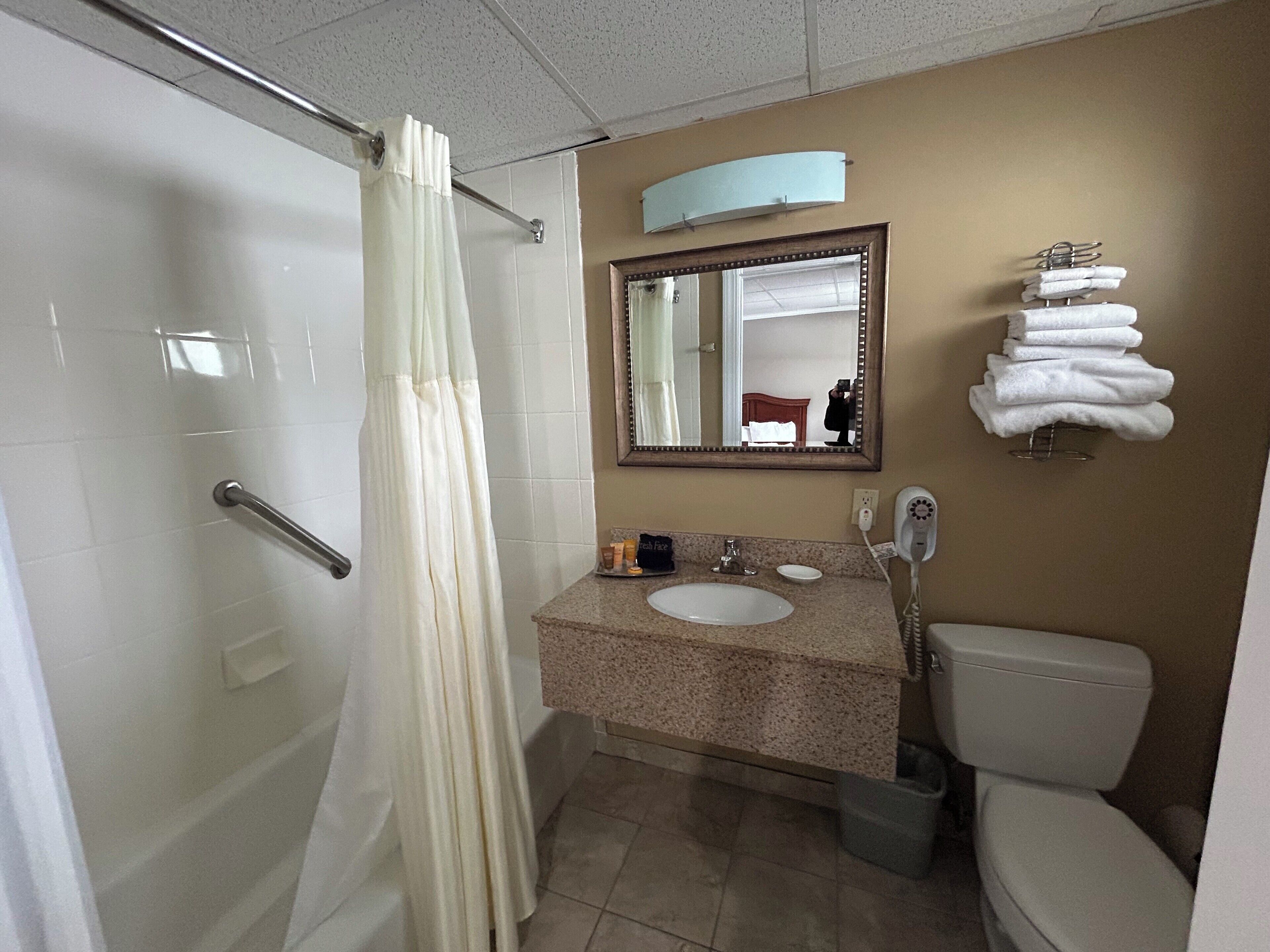 Un baño con ducha, lavabo, inodoro y espejo.