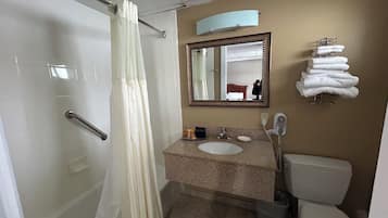 Un baño con ducha, lavabo, inodoro y espejo.