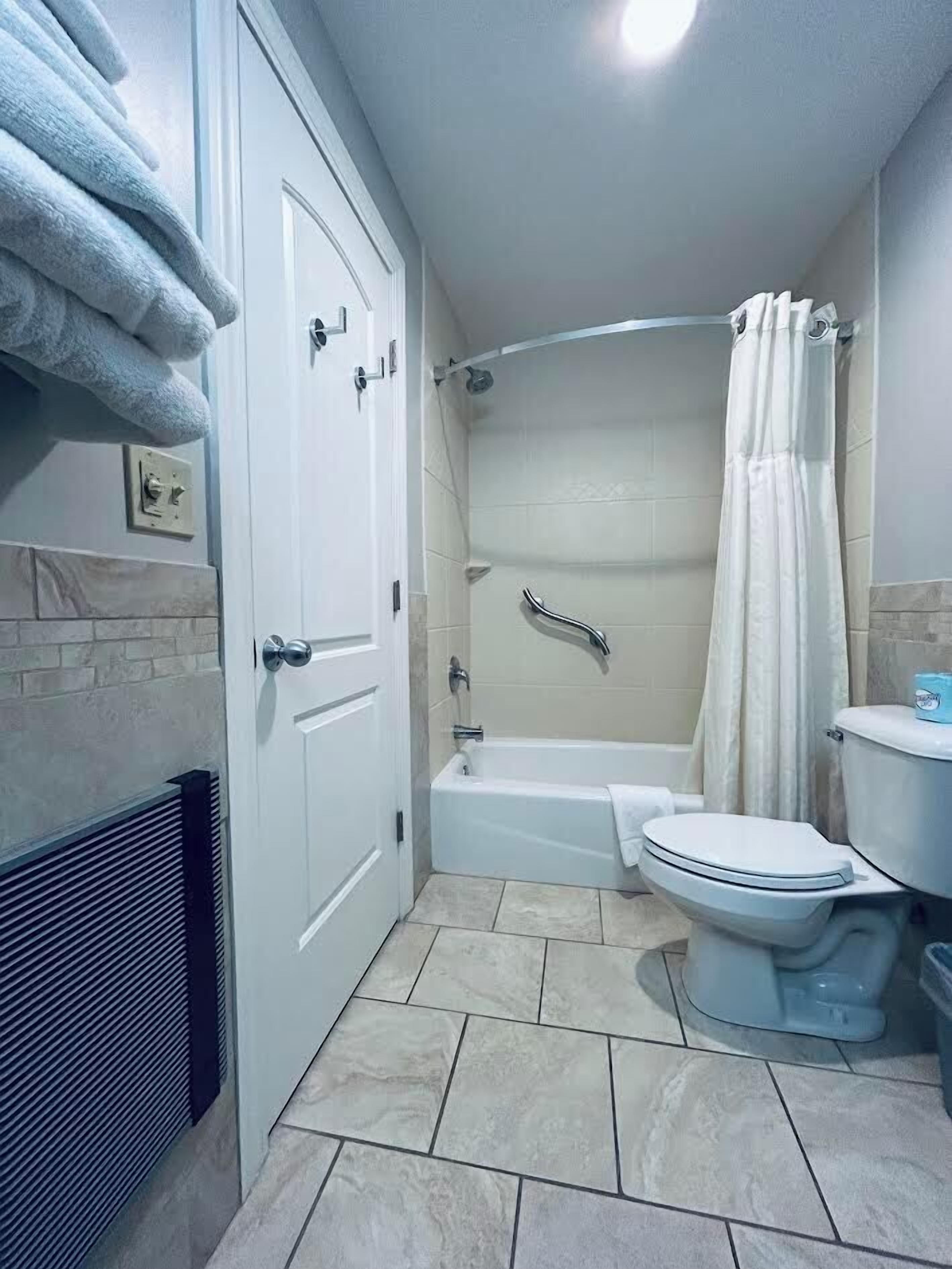 A bathroom with a bathtub, toilet, and shower curtain.