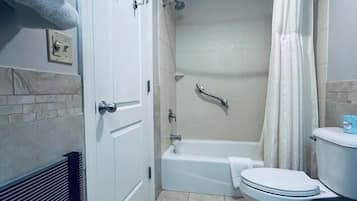 A bathroom with a bathtub, toilet, and shower curtain.