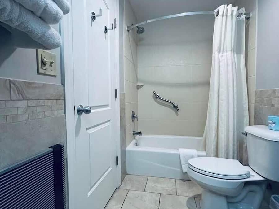 A bathroom with a bathtub, toilet, and shower curtain.