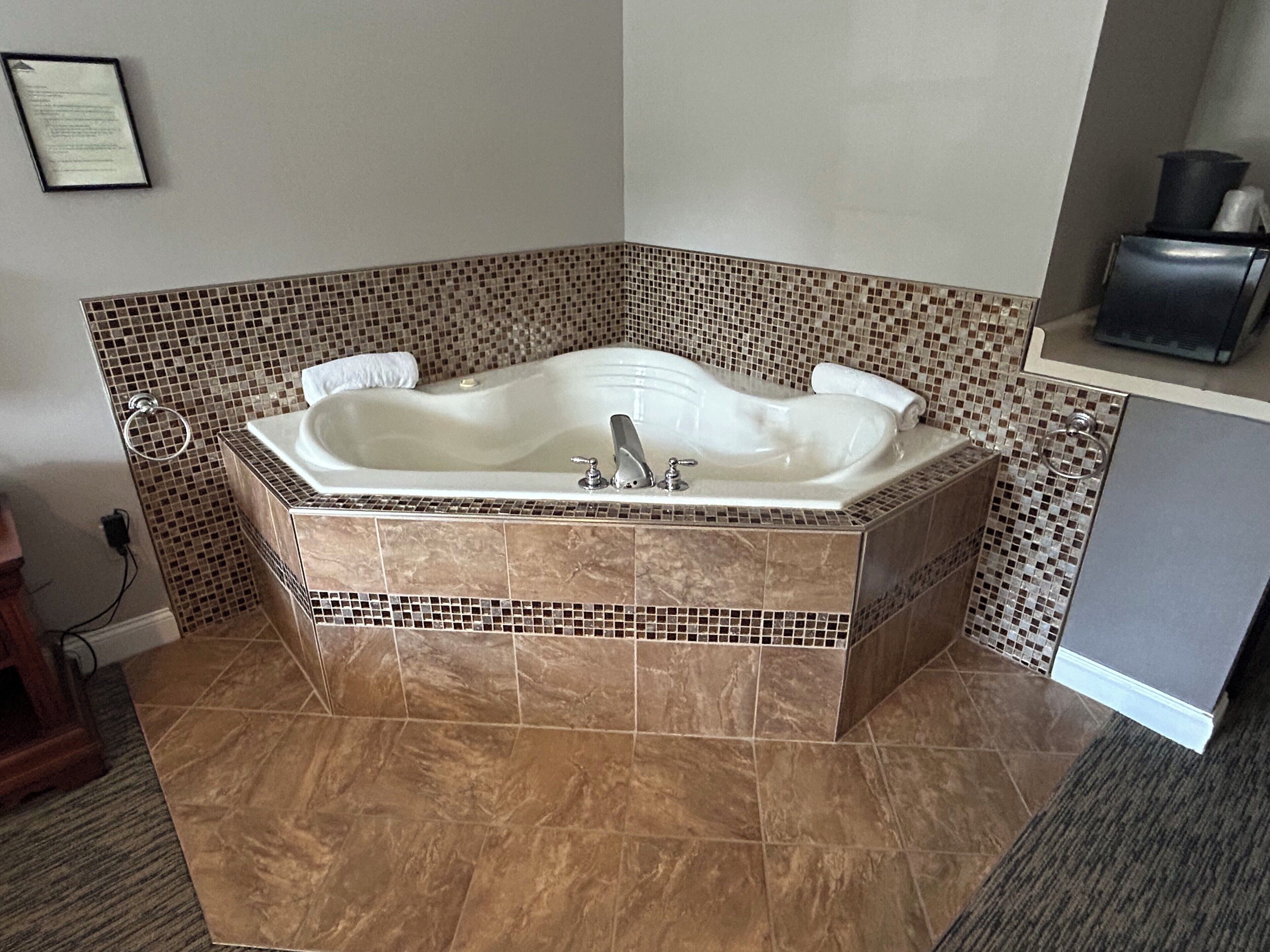A corner bathroom with a freestanding bathtub, tiled walls, and a marble floor.