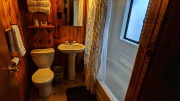 A wooden bathroom with a toilet, sink, and bathtub.
