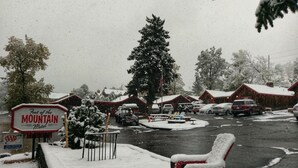 Un motel appelé « Au pied de la montagne », avec une enseigne, des places assises à l’extérieur et un environnement enneigé.