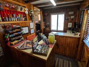 A rustic interior with wooden walls, a reception desk, various snacks, and a large window. - Foot of the Mountain Motel (Boulder)