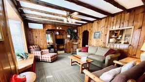 A cozy cabin-style room with wooden walls and ceiling, a sofa, a chair, a small table, and a telephone. - Foot of the Mountain Motel (Boulder)