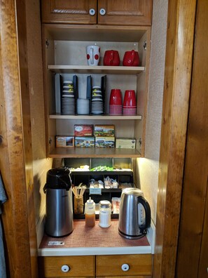 Una kitchenette con cafetera, azúcar, miel y leche de soja.