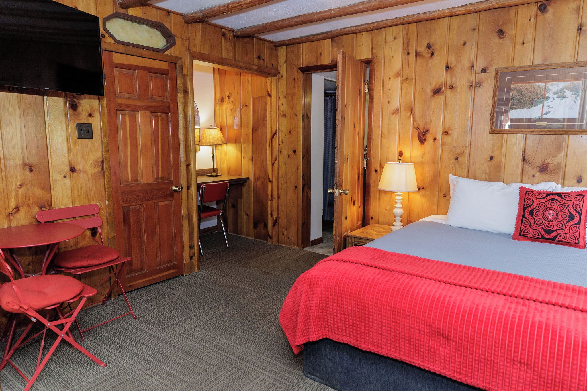 Une pièce en bois avec un lit, un bureau et deux chaises.