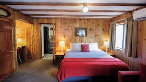 A wooden-paneled room with a bed, two bedside tables with lamps, a door, and a window with curtains. - Foot of the Mountain Motel (Boulder)