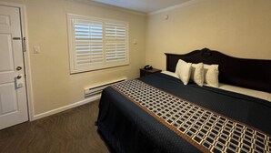 A bedroom with a bed, a nightstand, a window with blinds, a door, and a ceiling light. - Tamalpais Motel (Mill Valley)