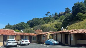 A parking lot with several cars and a covered vehicle. - Tamalpais Motel (Mill Valley)