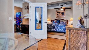A bedroom with a bed, a ceiling fan, a mirror, and a lamp. - Island Bay Resort (Tavernier)