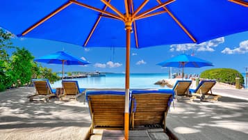 Een privéstrand, ligstoelen aan het strand, parasols, strandlakens