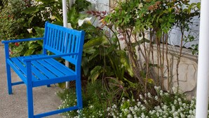 A blue bench outside a building with hanging flower baskets. - La Kris Inn (Bandon)