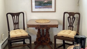 A room with two wooden chairs with cushioned seats, a small wooden table with a woven placemat, and a framed picture on the wall. - La Kris Inn (Bandon)