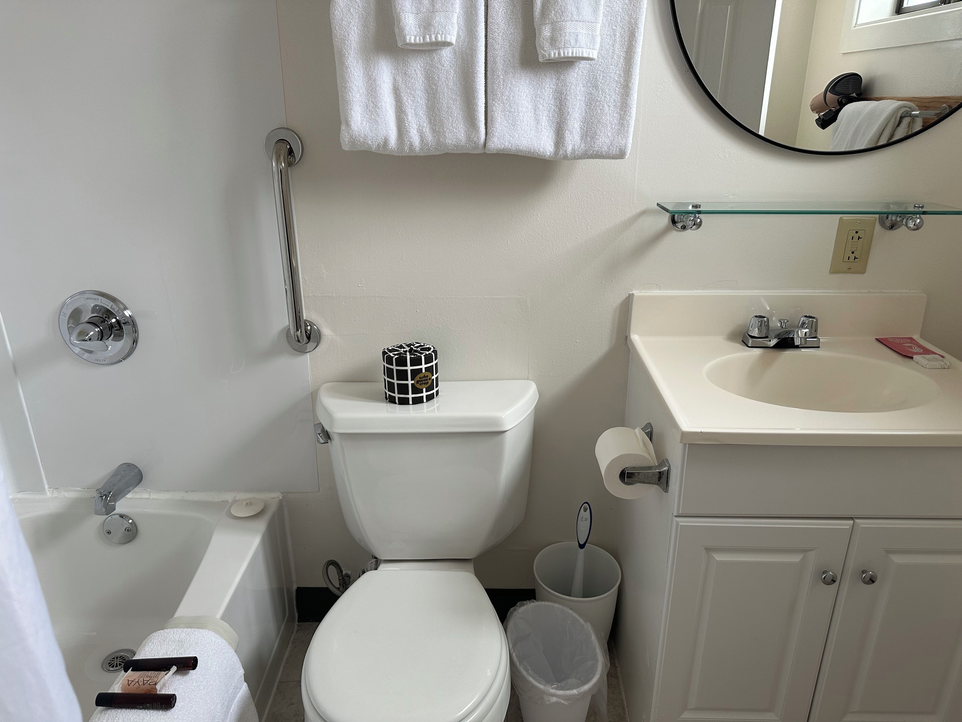 Un baño con inodoro, bidé, repisa de vidrio, lavabo y espejo.