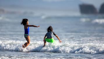 Zwei Kinder spielen im Meer mit Wellen.