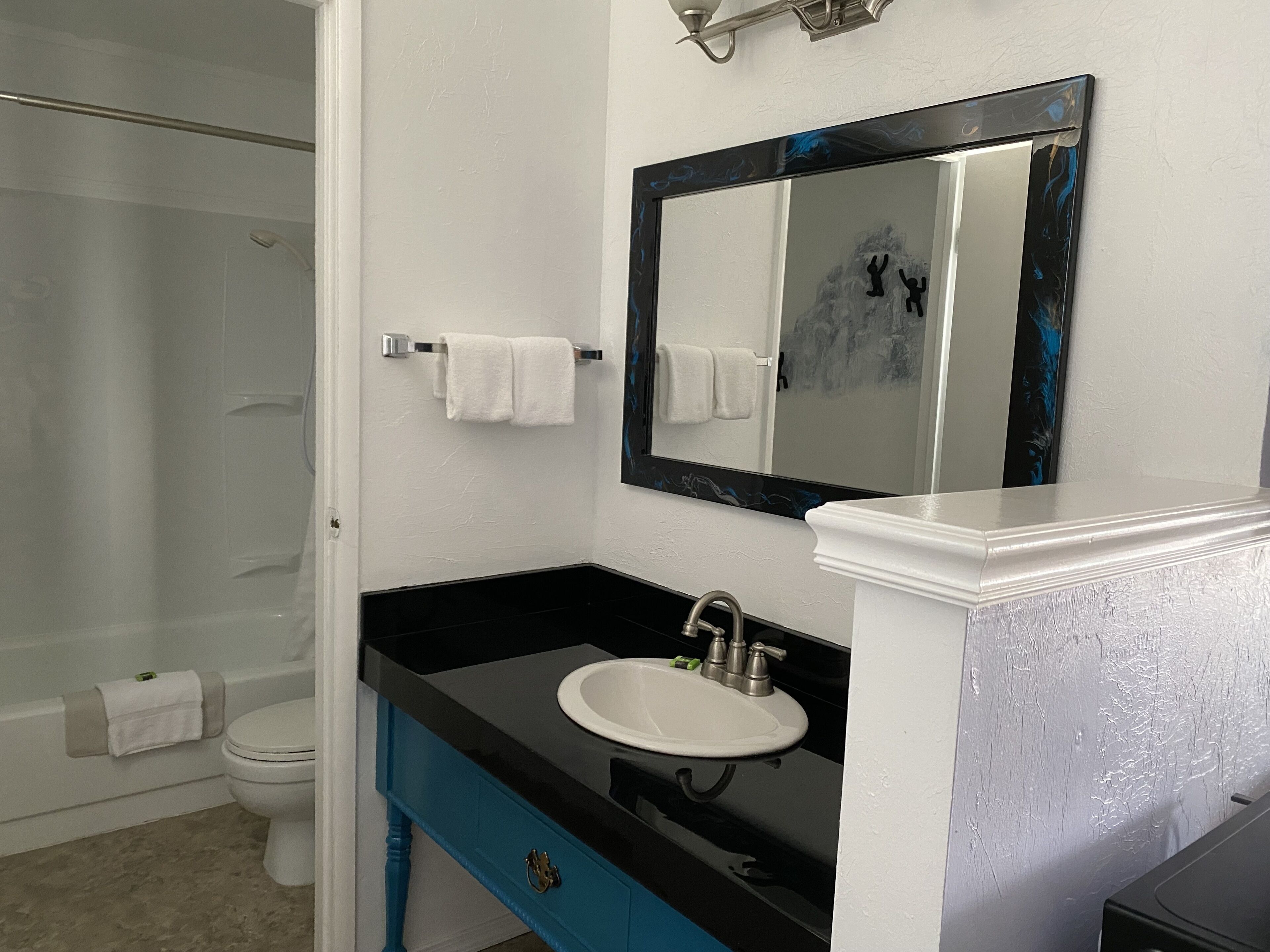 Ein Badezimmer mit schwarzem Waschbecken, weißer Toilette und einer Duschkabine.