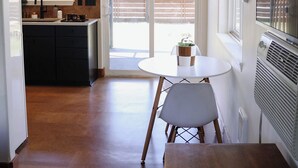 A modern kitchen with a sink, stove, and window. There is a dining area with a table and chairs. - The Stranger Lodge (Sisters)