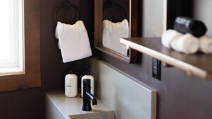 A bathroom with a mirror, towel rack, sink, and toiletries. - The Stranger Lodge (Sisters)