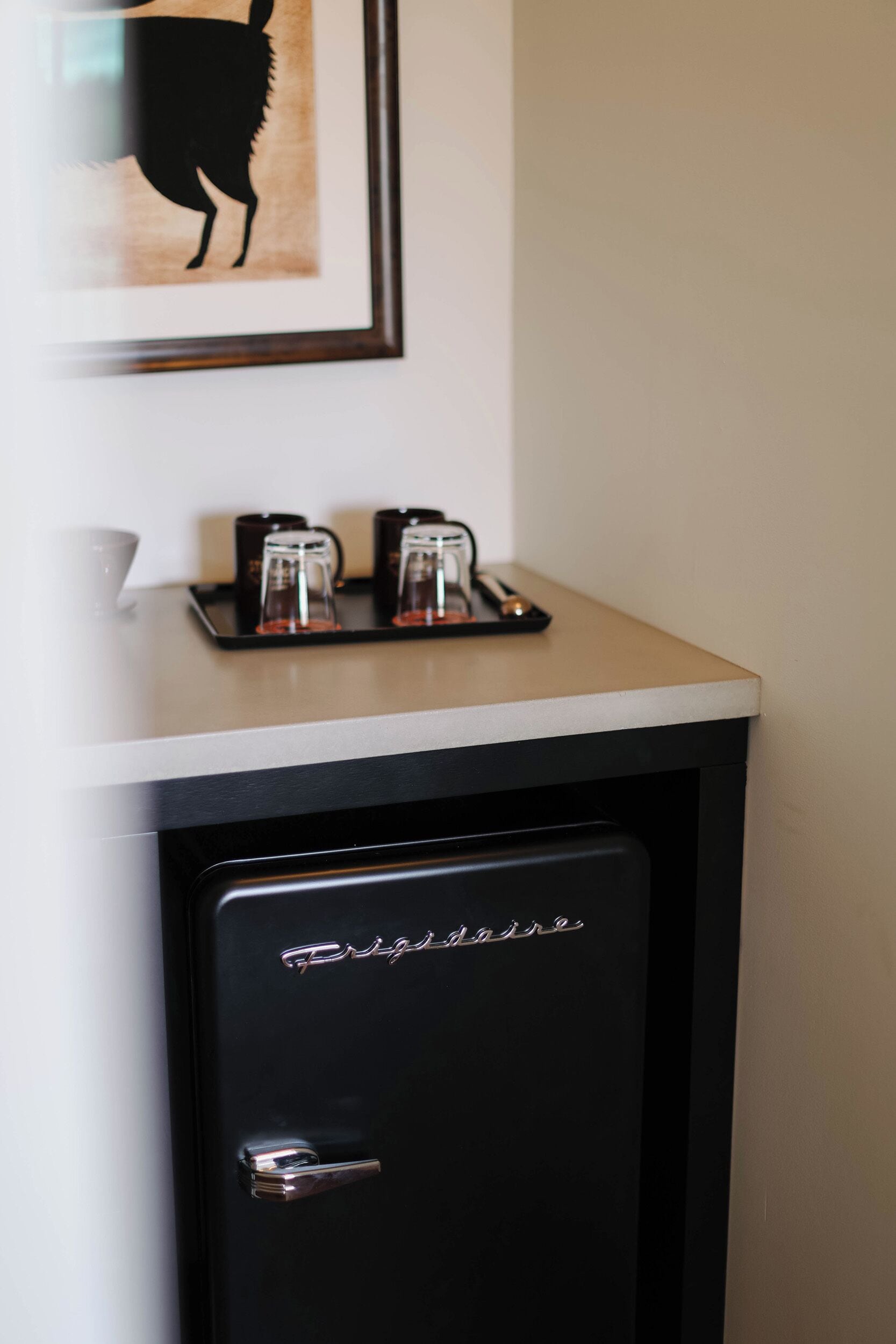 A small black refrigerator with a handle and a door with a brand name.
