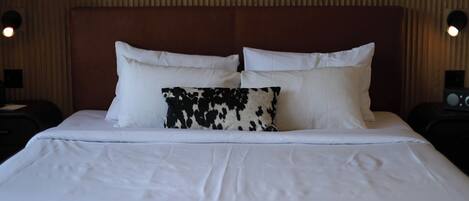 A hotel room with a large bed, two bedside tables, and a wooden headboard.
