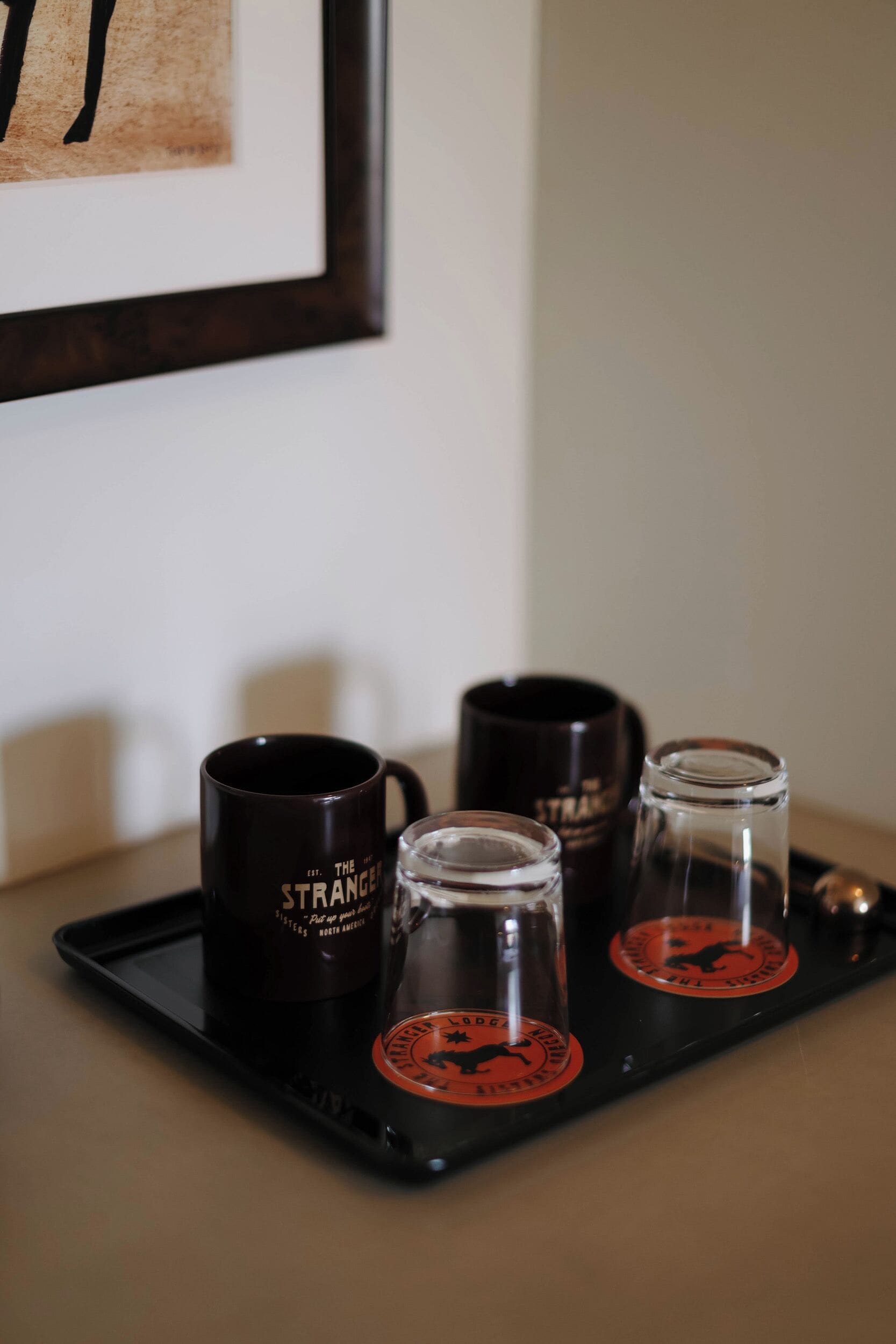 A tray with two coffee mugs and two glasses on a table.