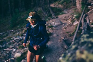 A person hiking on a rocky trail surrounded by trees. - The Stranger Lodge (Sisters)